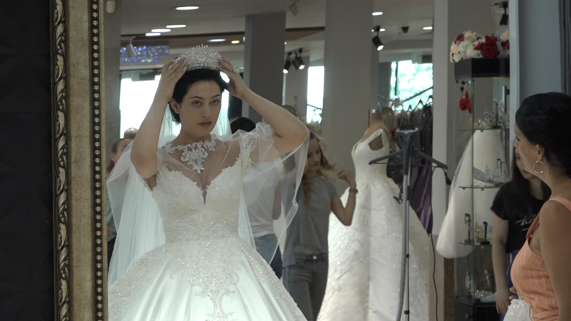 Donna in abito da sposa che si sta sistemando il velo davanti a uno specchio.