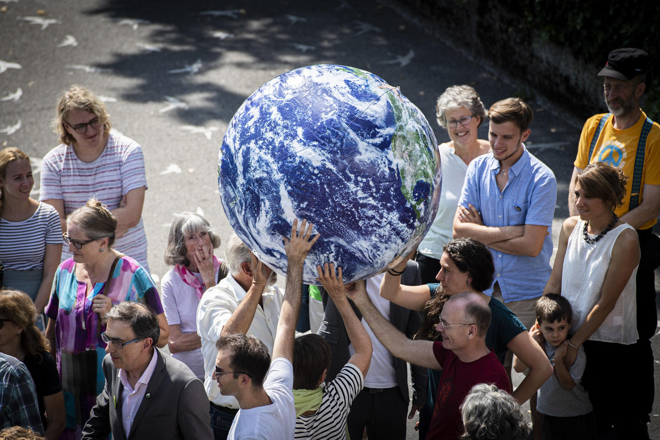 gente cammina per strada portando un globo terrestre