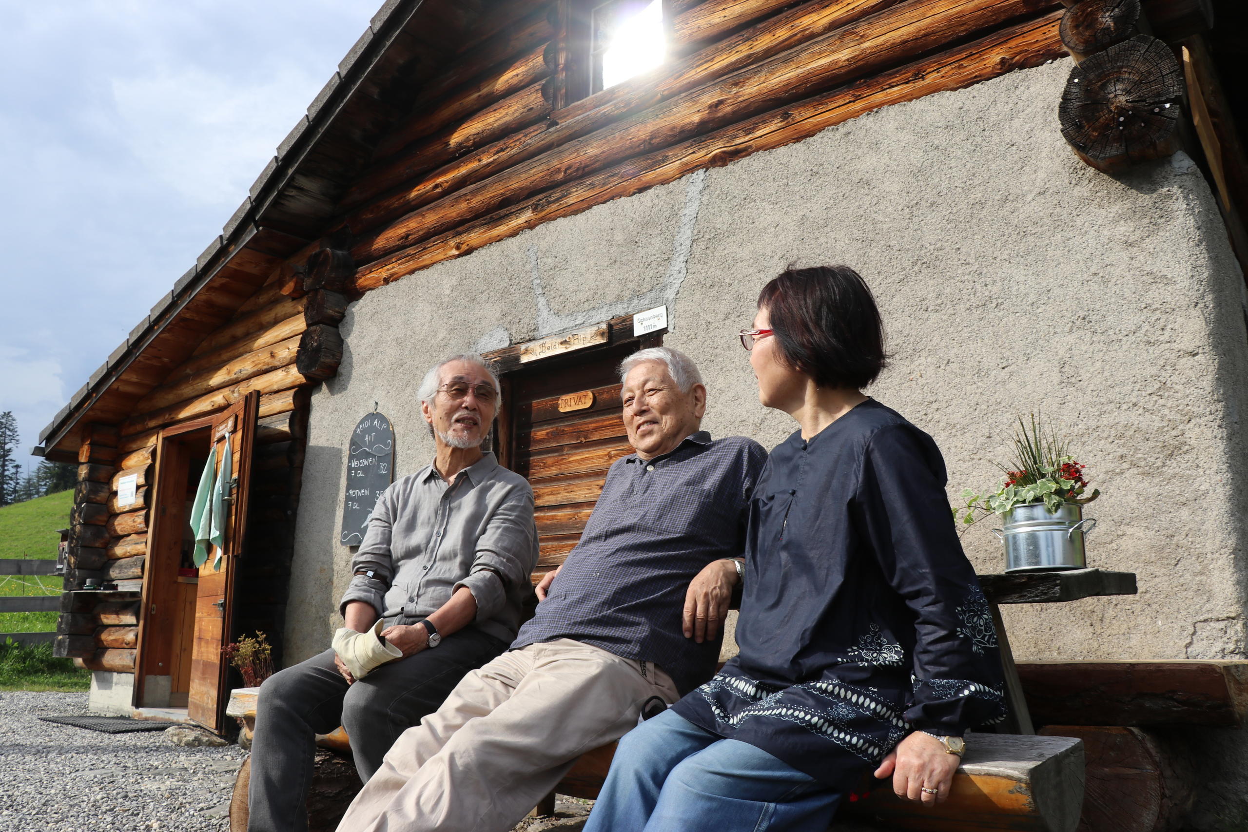 three people in front of a hut