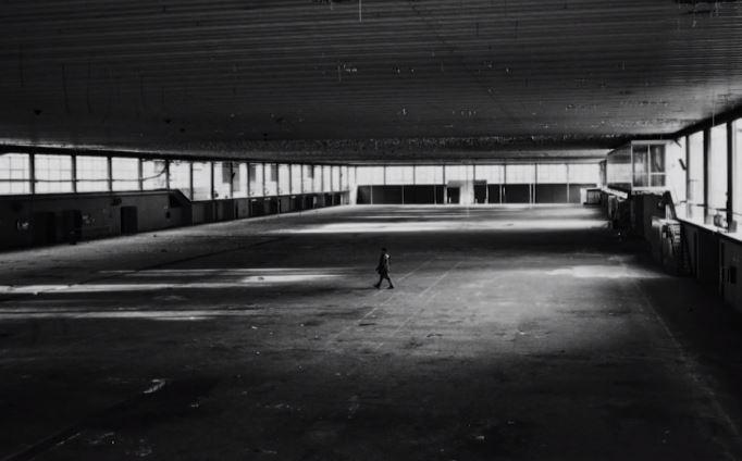 Un fotogramma del documentario: il regista piccolo piccolo in un capannone industriale completamente vuoto e fatiscente