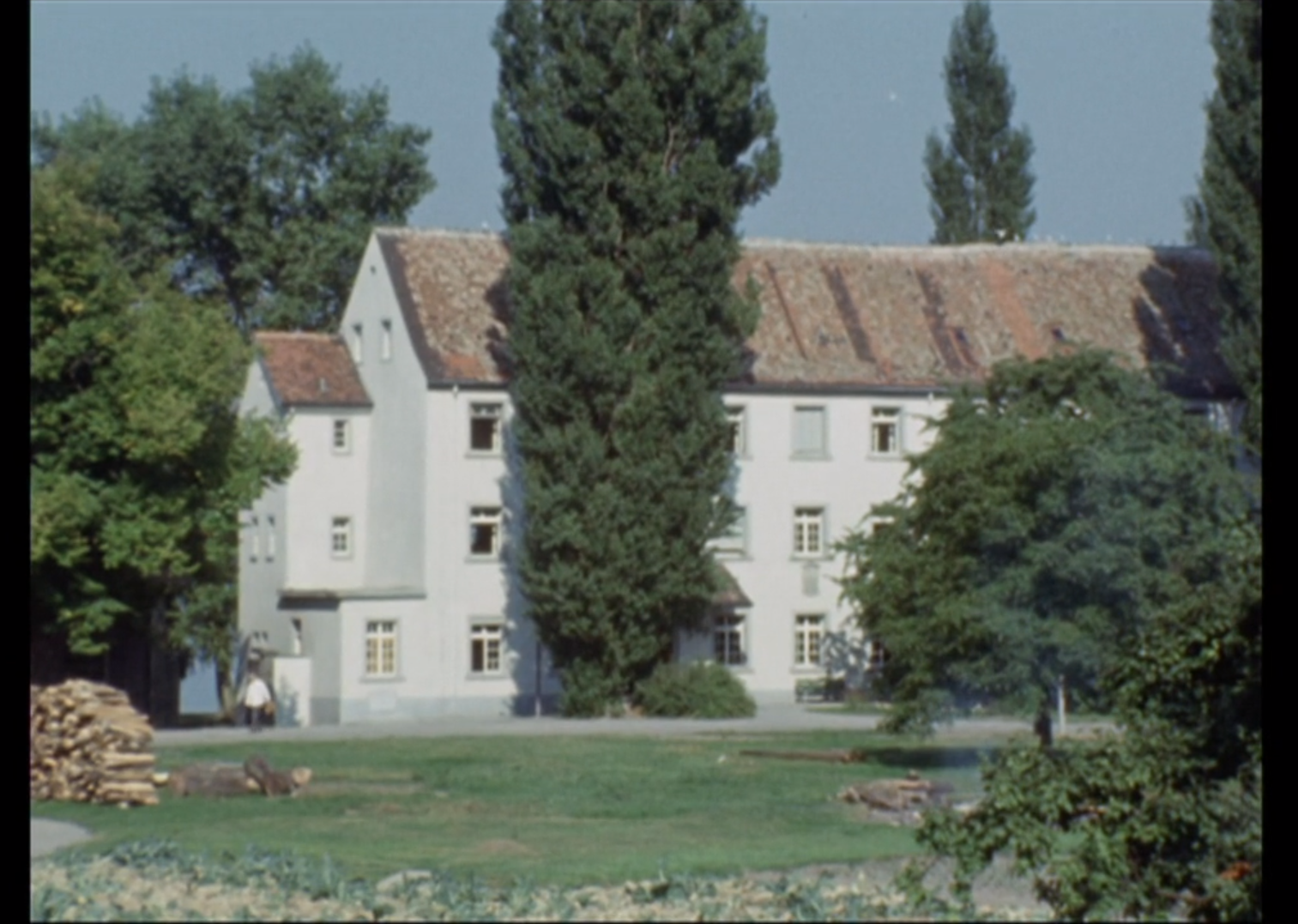 Immagine di uno grosso stabile,di architettura semplice, immerso in un parco e in riva a un lago