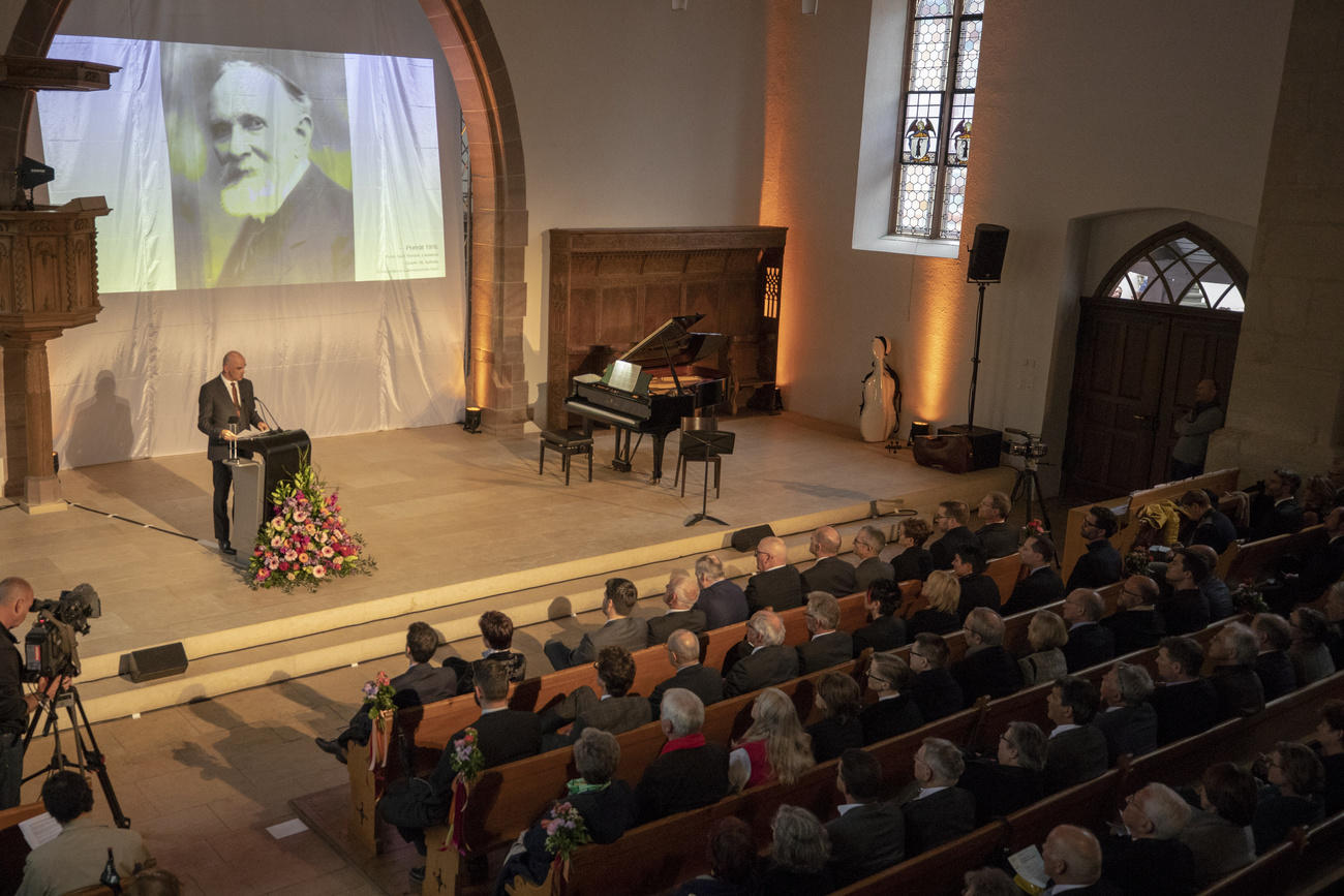 Man on a podium addressing an audience in a church