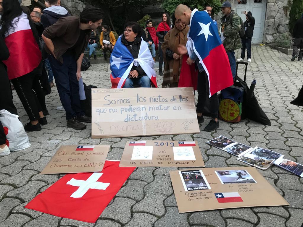 Personas con la bandera de Chile en los hombros y la bandera de Suiza y fotos en el suelo