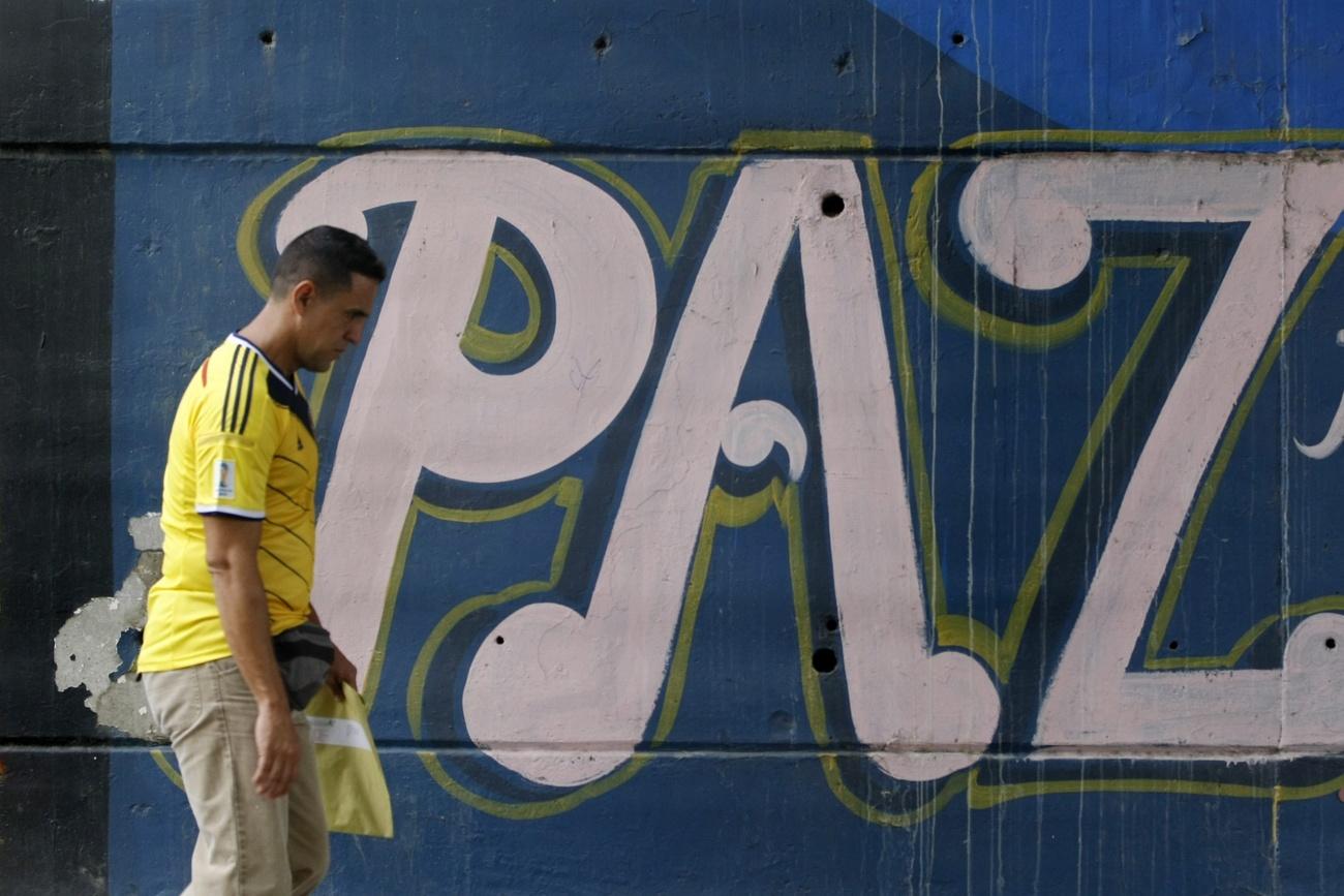 Un hombre pasa junto a una parada en la que se lee: PAZ