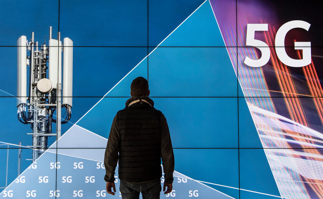 Mann steht mit dem Rücken zur Kamera vor einem Plakat mit 5G-Antenne