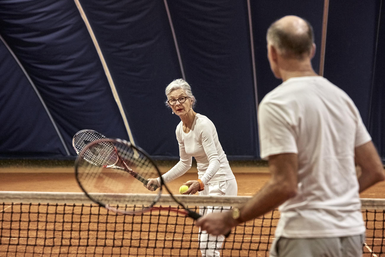 Pareja de personas mayores juega al tennis.