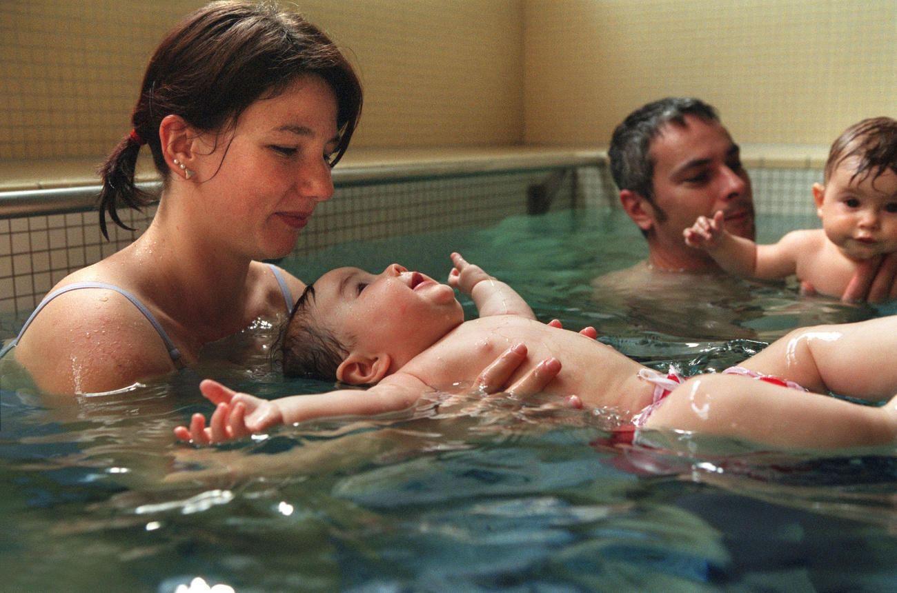 Eine Frau und ein Mann mit zwei Babys im Wasser.