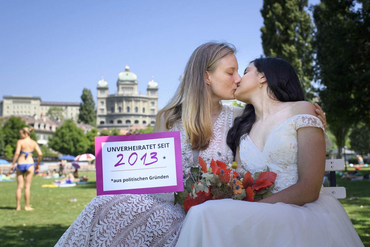 Deux femmes en robe de mariées qui s embrasse, avec le Palais fédéral en toile de fond