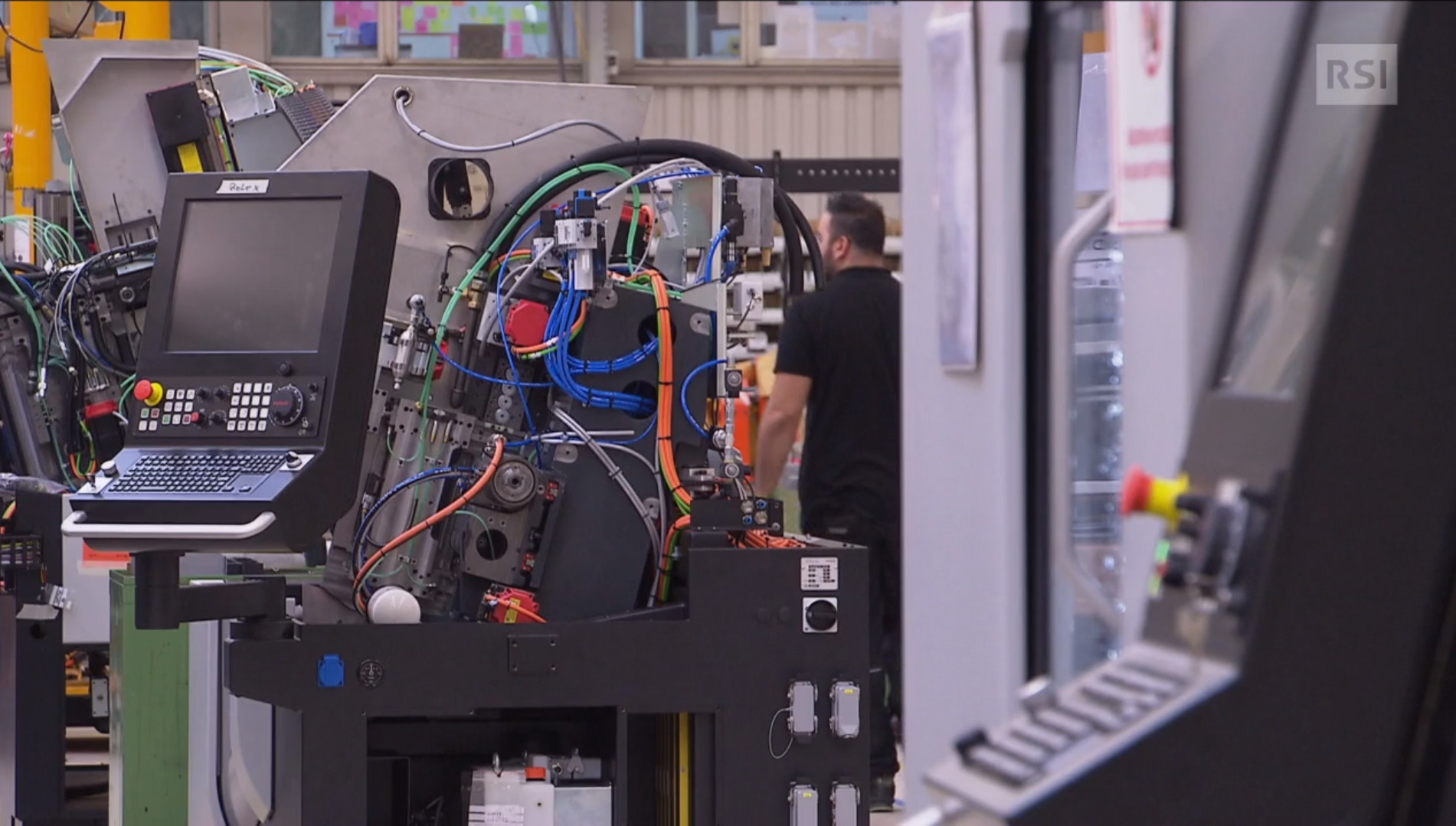 Interno di uno stabilimento con macchine altamente informatizzate; operaio in lontananza