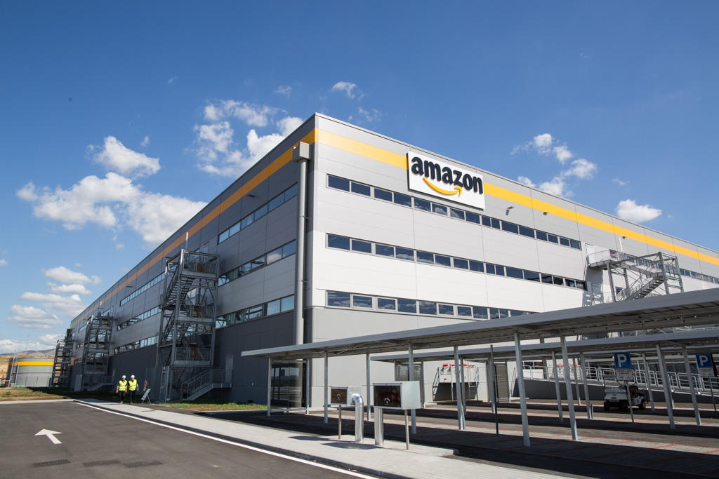 Stabile industriale con parte a tre piani e insegna Amazon ritratto in una giornata di sole