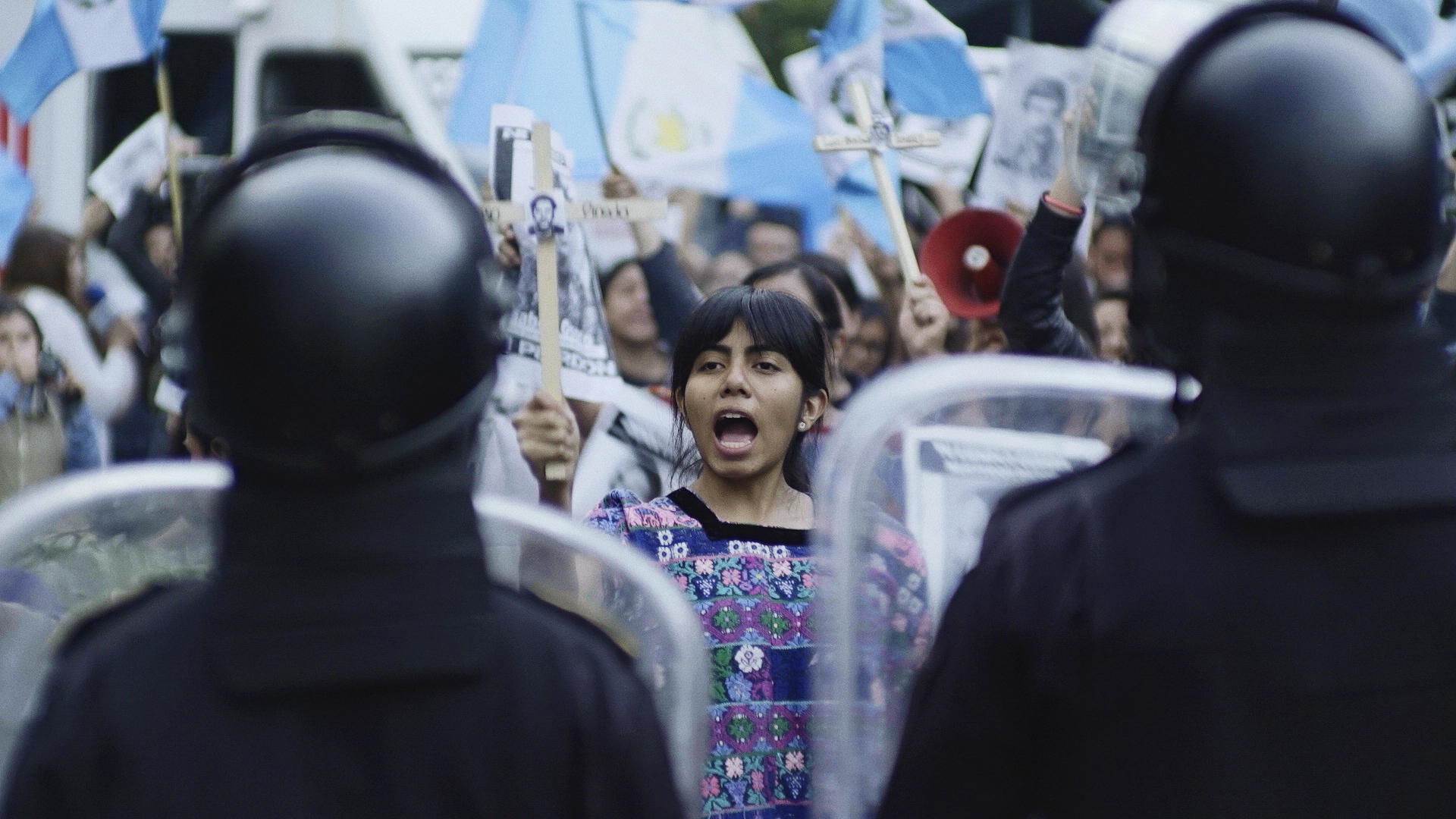 Una mujer frente a policías en una manifestación