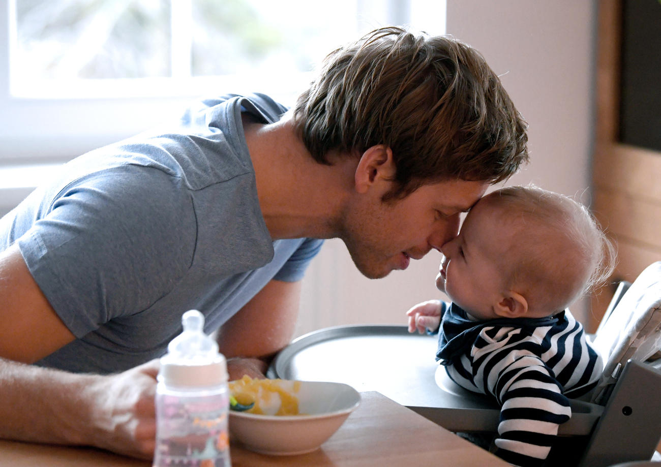 Un papà sta dando da mangiare al figlio di meno di un anno.