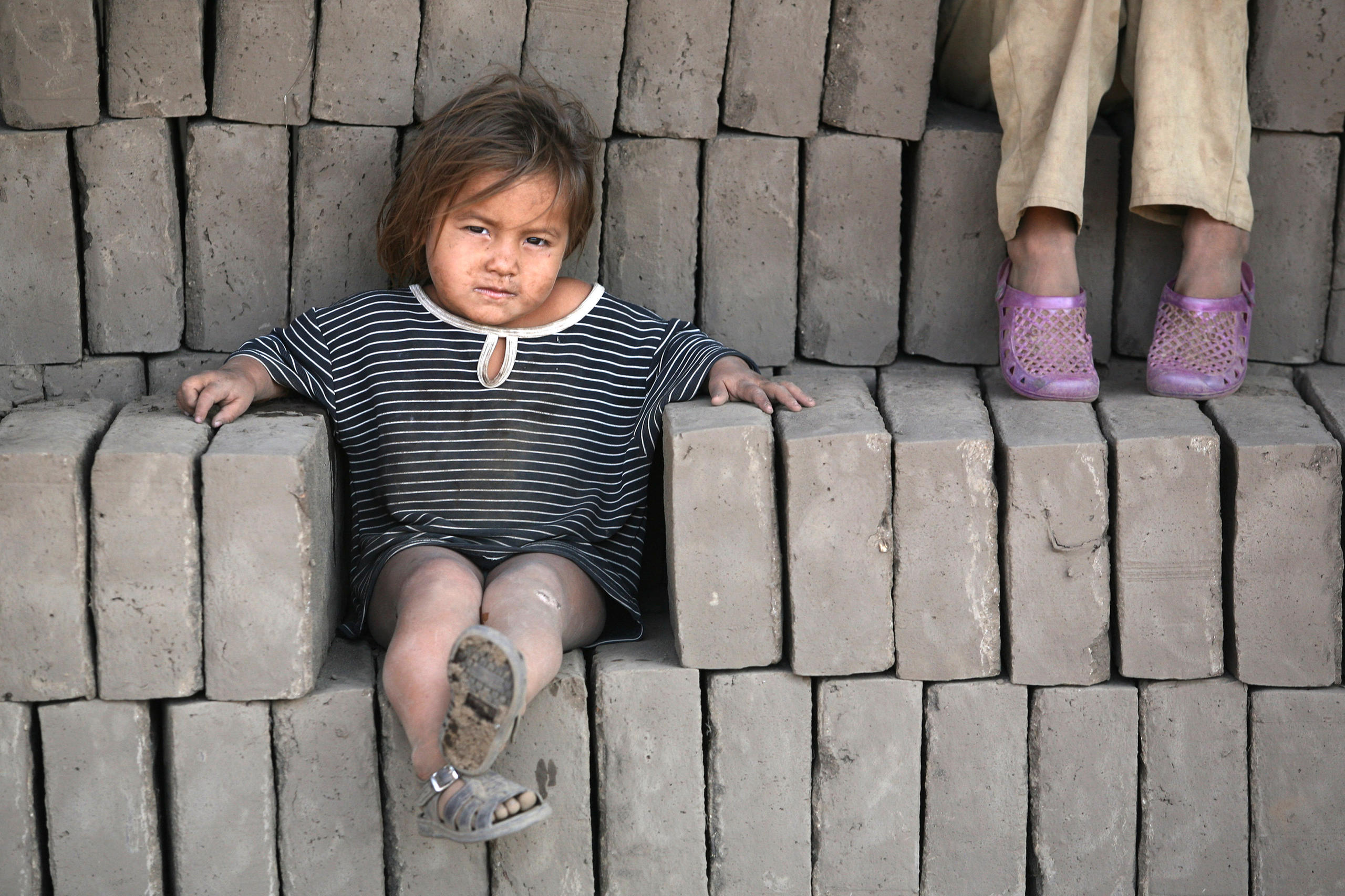 طفل يجلس وسط قوالب حجرية تستخدم في بناء البيوت
