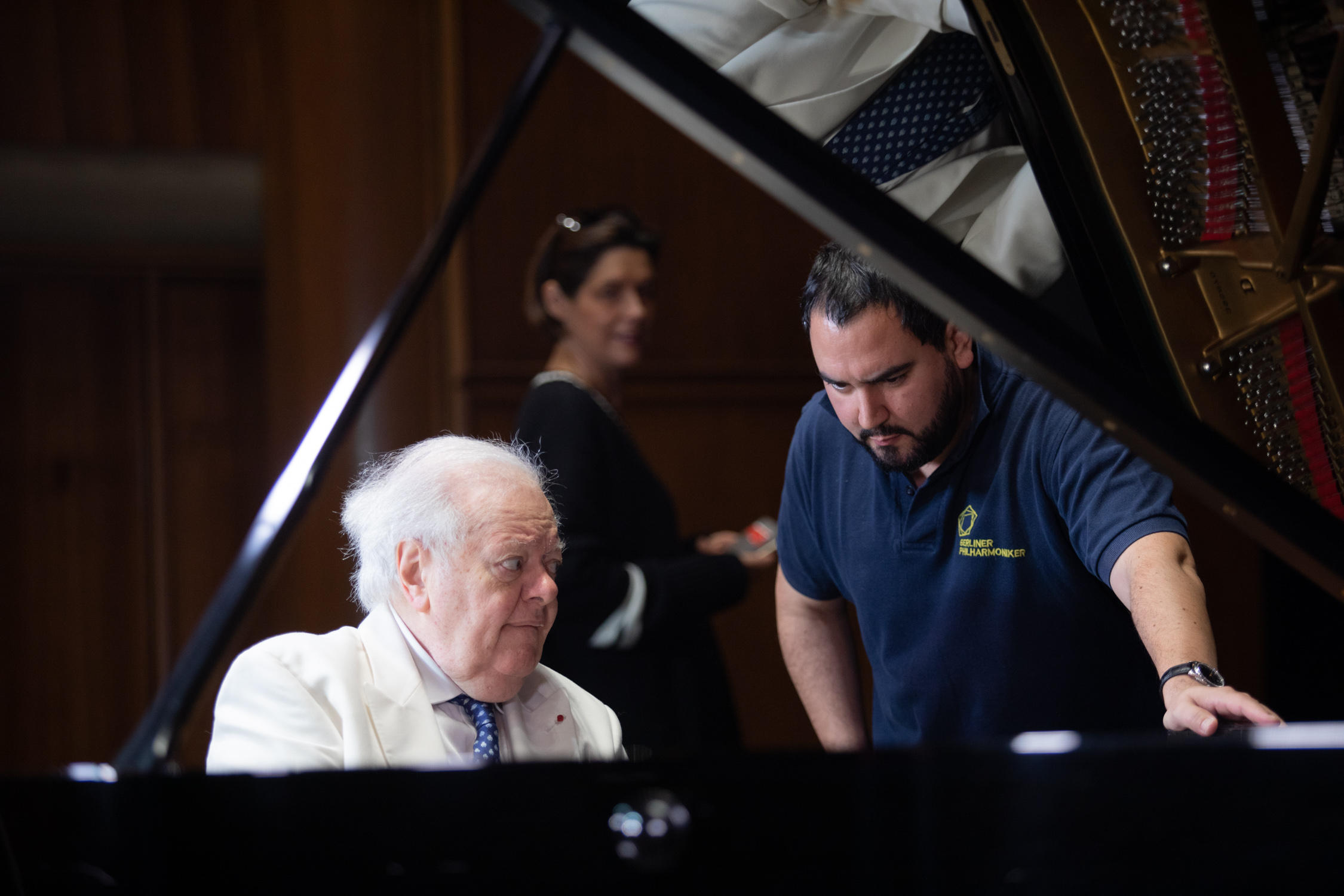 Un pianiste entouré de deux personnes.