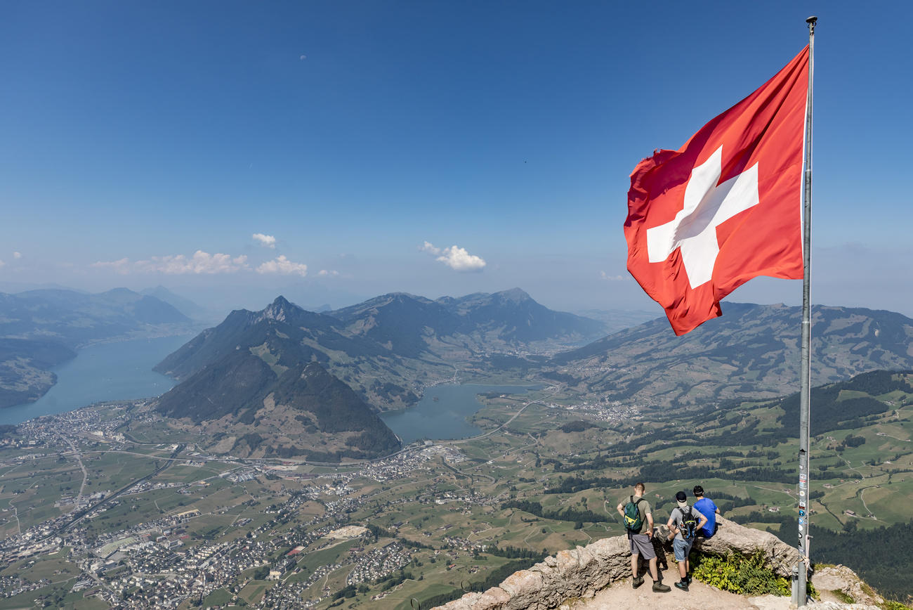 Grupo de hombres y bandera suiza en la cima de una montaña