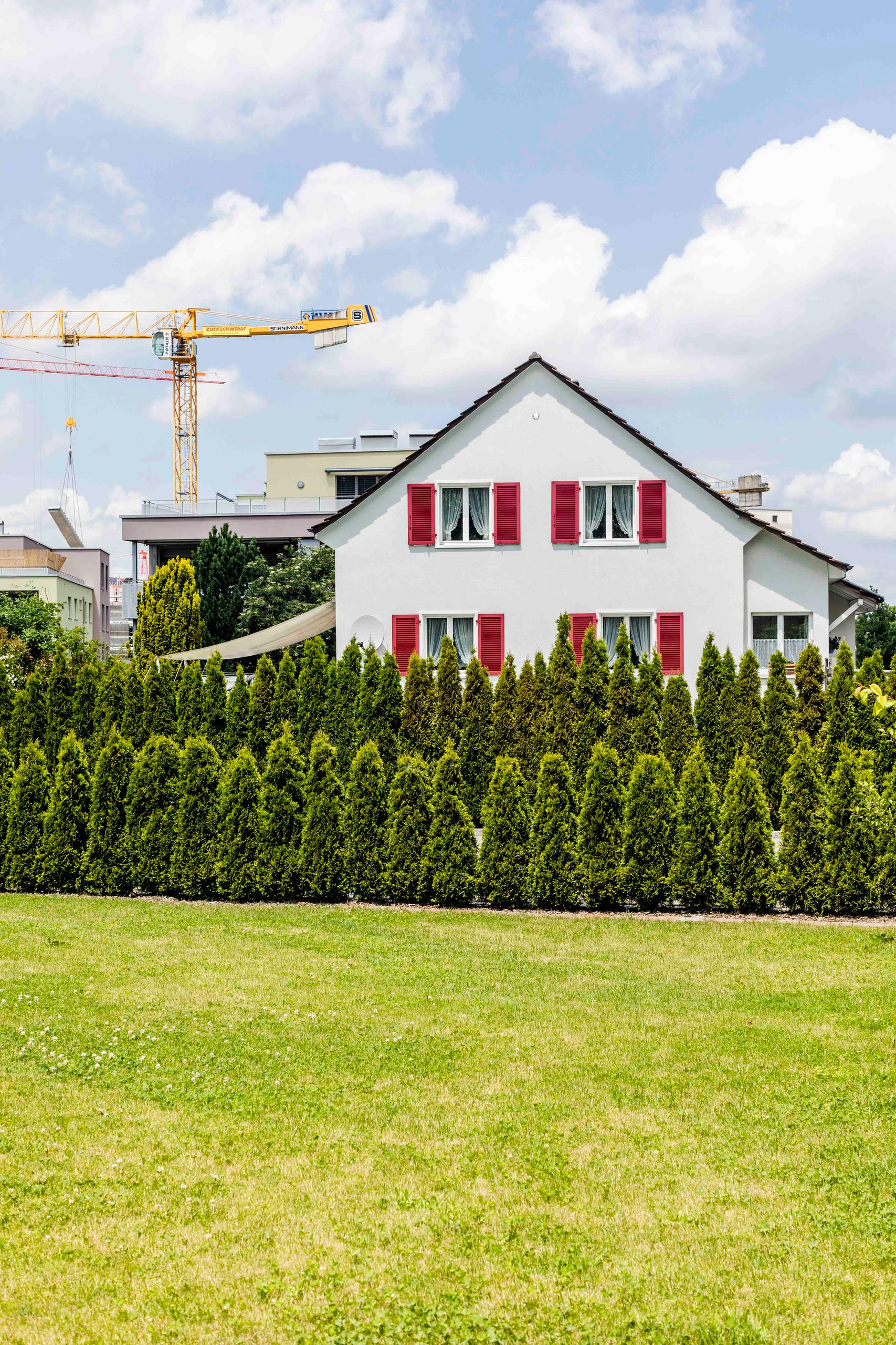 Altes Haus vor Baukränen