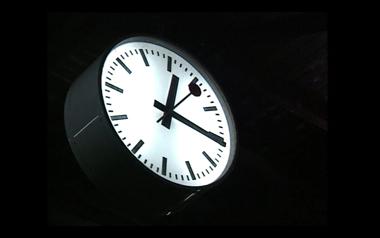 Un orologio di stazione svizzera ripreso in piena notte: si vedono solo quadrante e lancette