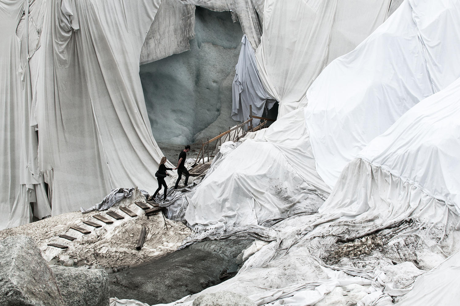 Glaciers draped with cloth, two people walk along the steps.