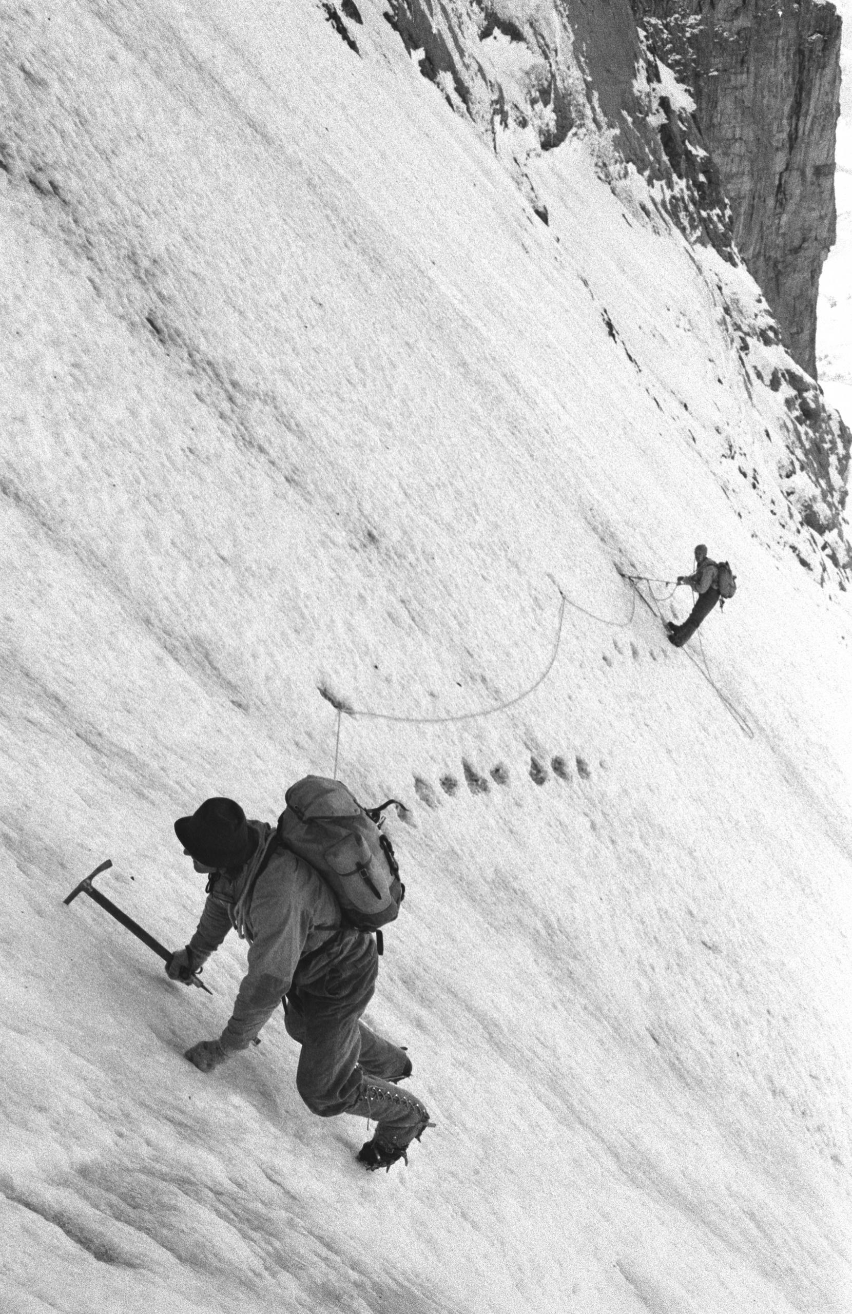 Dos alpinistas ascienden una montaña.