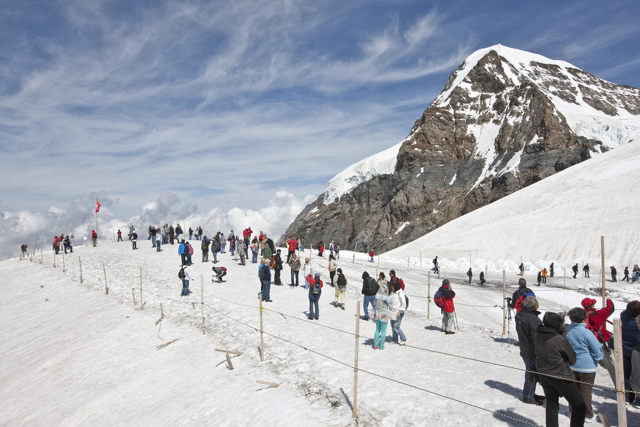 Many people walk across snowfield on the Jungfraujoch.