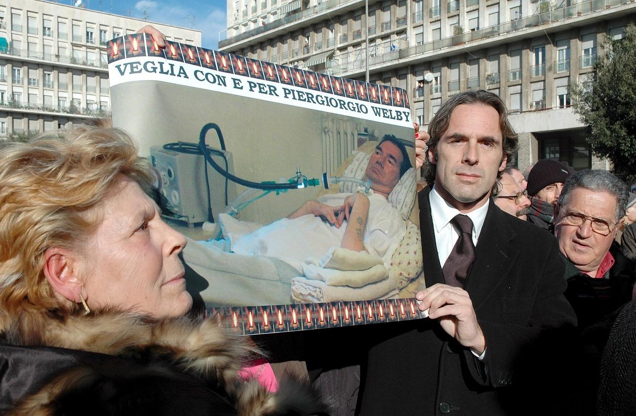 due persone con un manifesto con una foto di Piergiorgio Welby