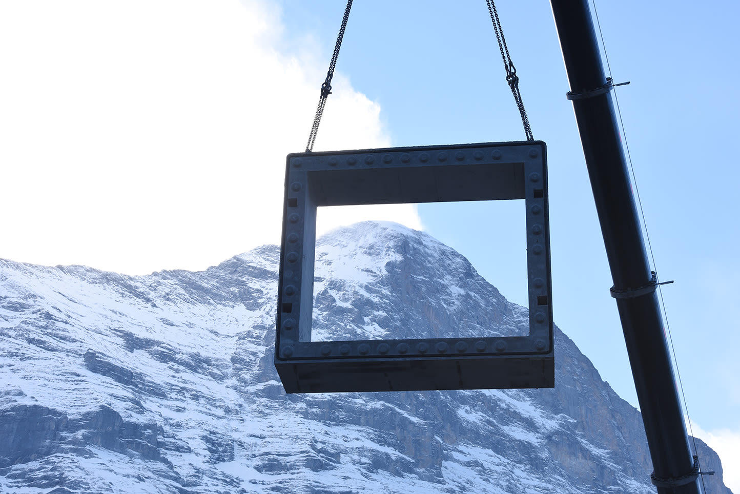 Crane hoists a frame, with Eiger summit in background