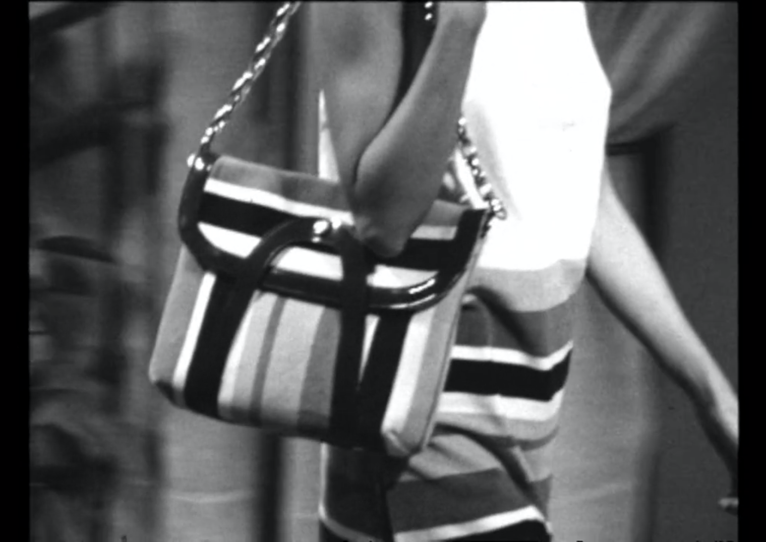 Una borsetta a righe, indossata sul fianco destro di una donna, ripresa da vicino (in b/n)