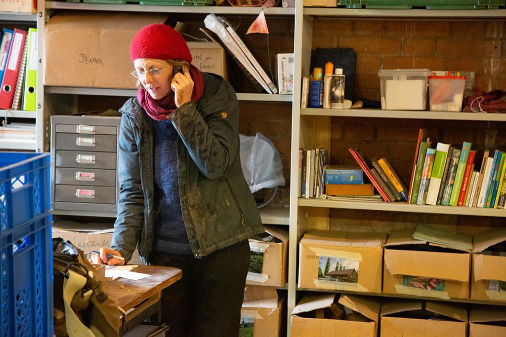 Femme debout devant un bureau en train de téléphoner.