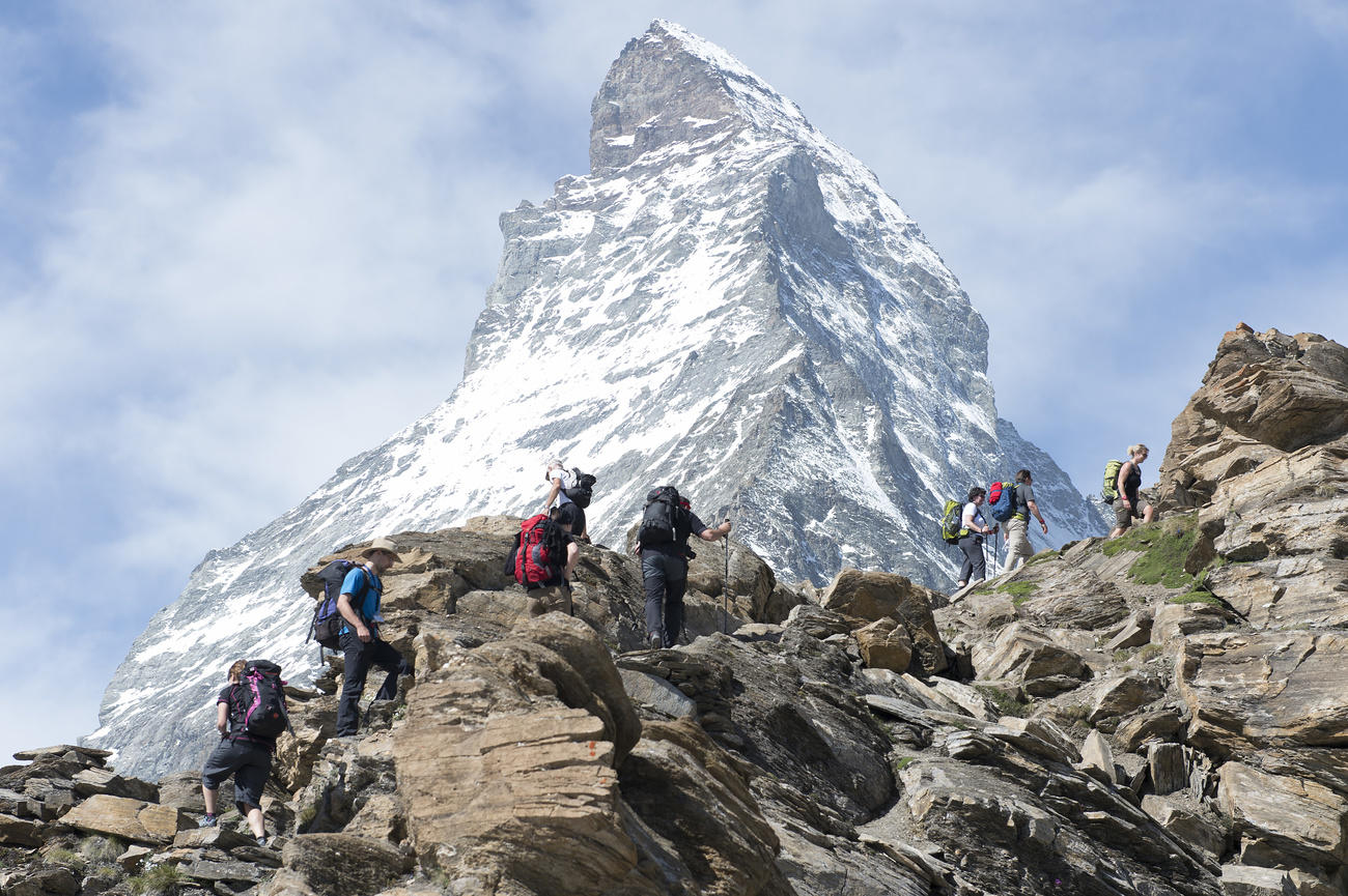 Una cordata di alpinisti in ascesa verso una montagna, che si riconosce essere il Cervino.