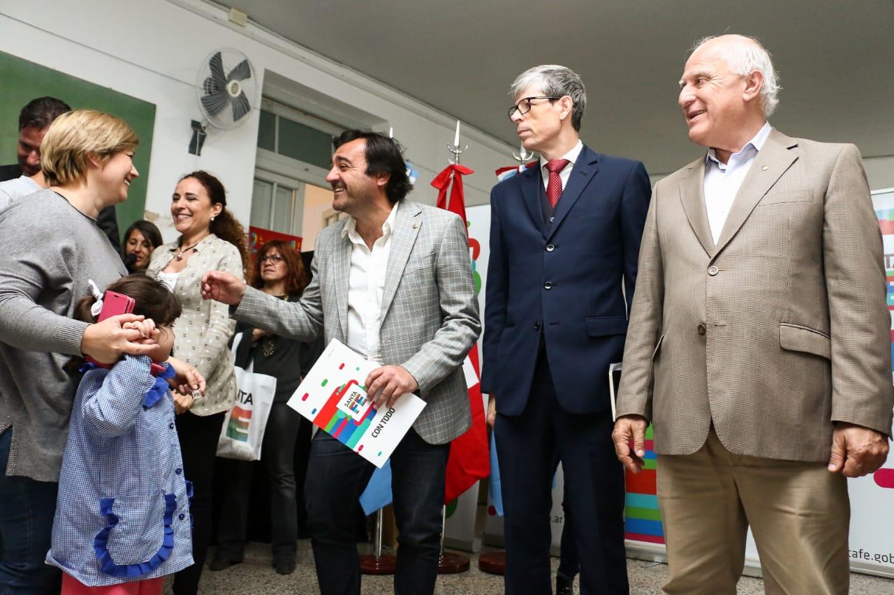 Uno hombre entrega un documento a una persona que no se ve. Lo acompañan otros dos hombres.