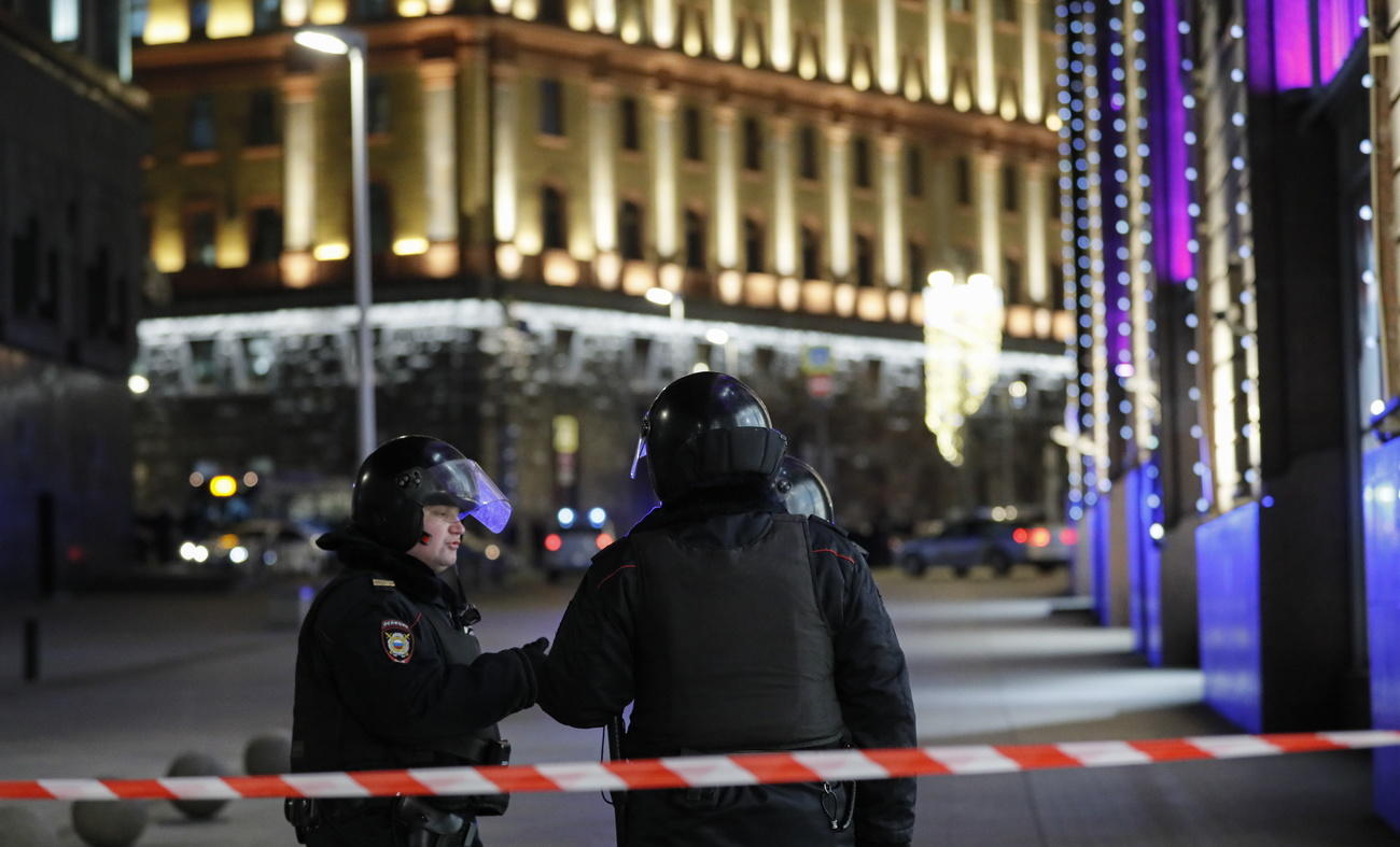 Due poliziotti in tenuta antisommossa poco oltre un nastro di delimitazione in un centro città con luminarie natalizie