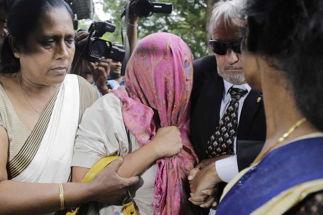 The Swiss embassy worker, with pink shawl, being escorted to a court in Colombo.