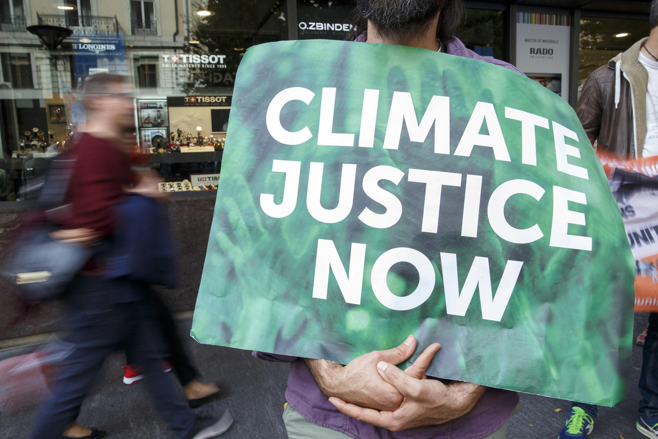 Climate protester holds sign saying Climate Justice Now