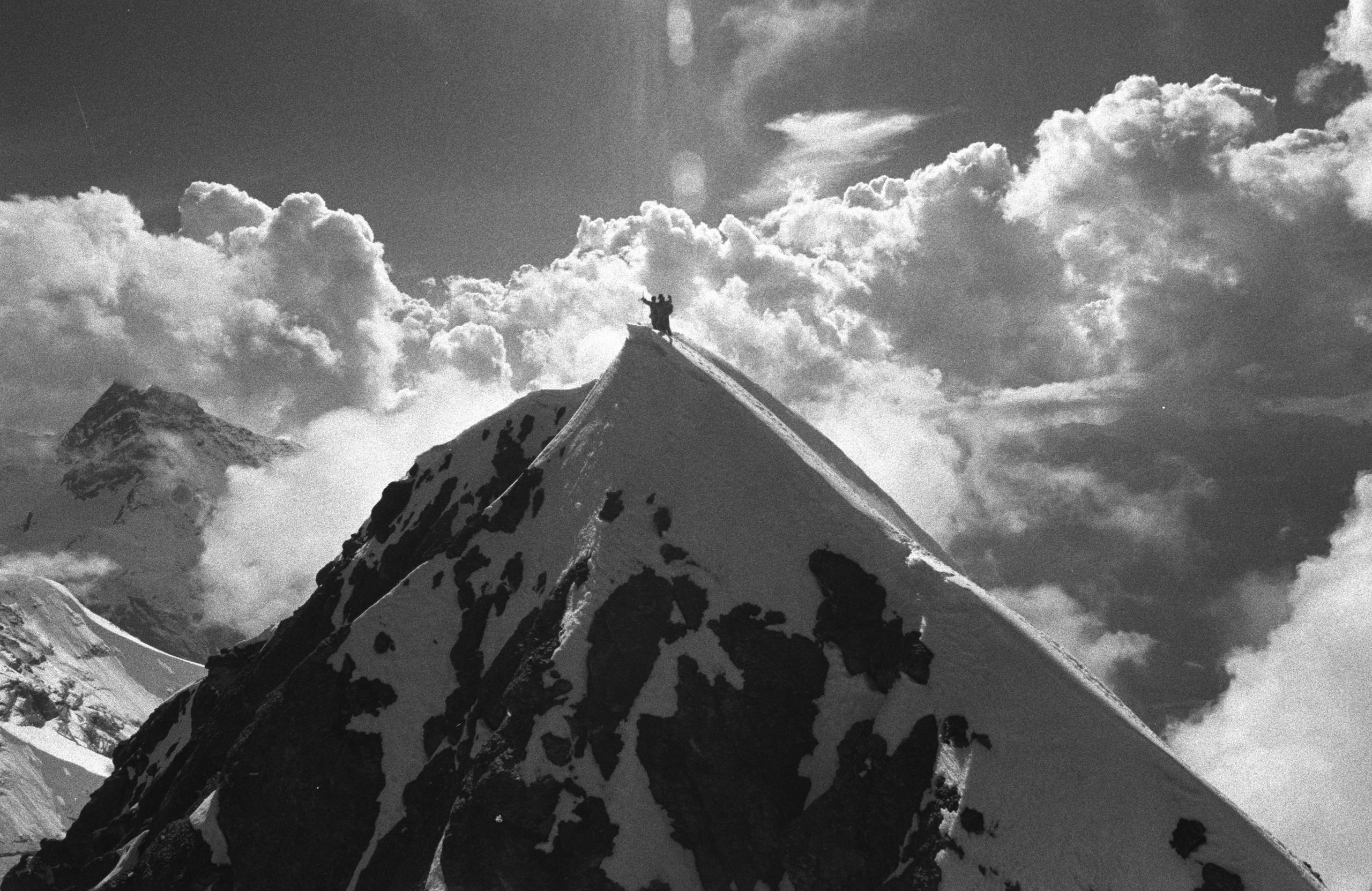 Vista panorámica de una montaña con dos hombres en la cima.