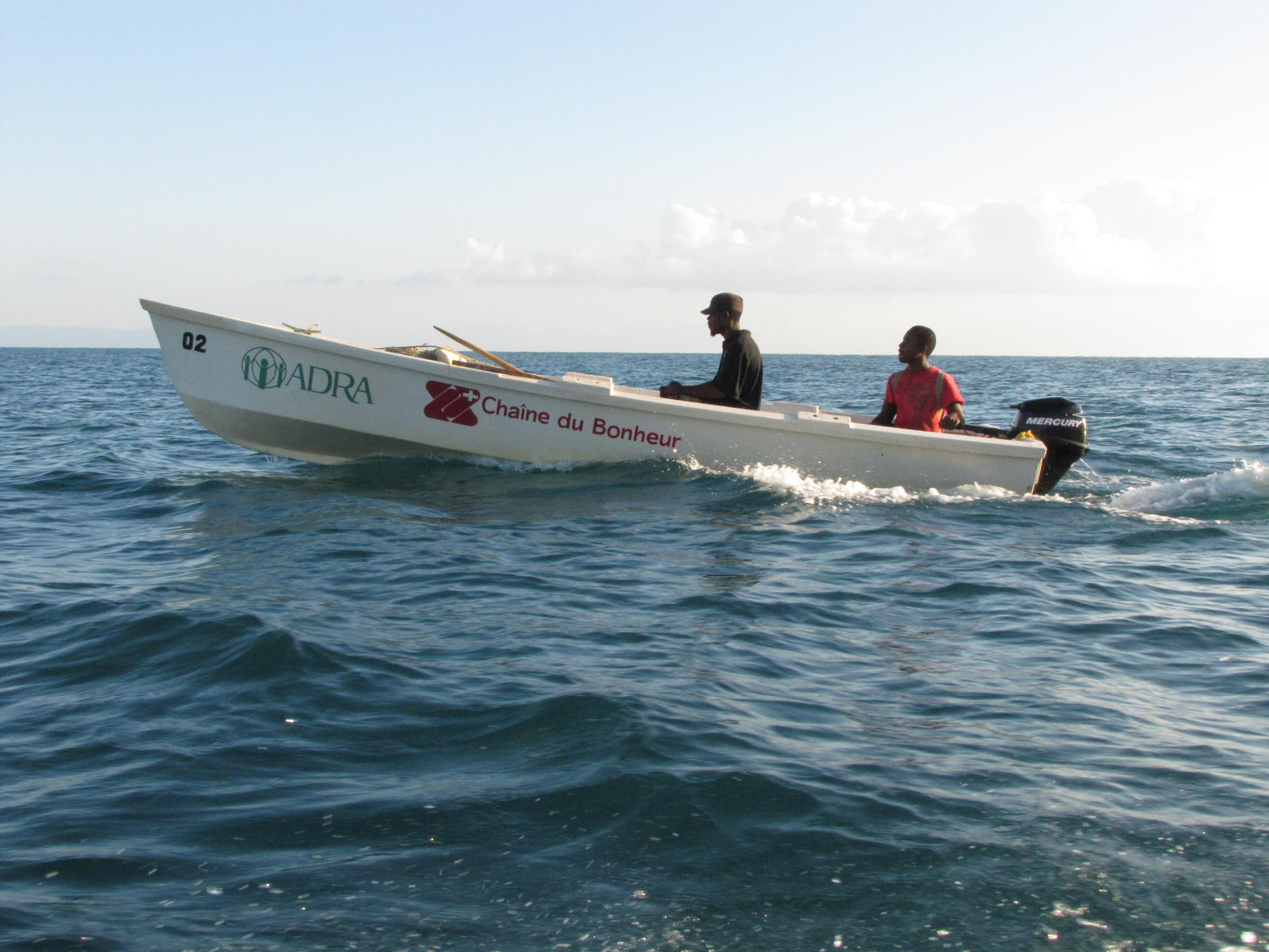 Zwei Männer fahren in einem weissen Boot aufs Meer hinaus.