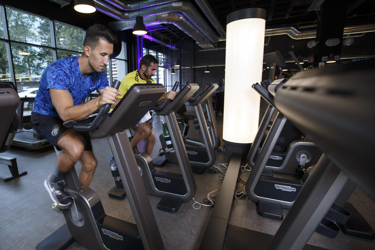 Due persone in palestra mentre pedalano