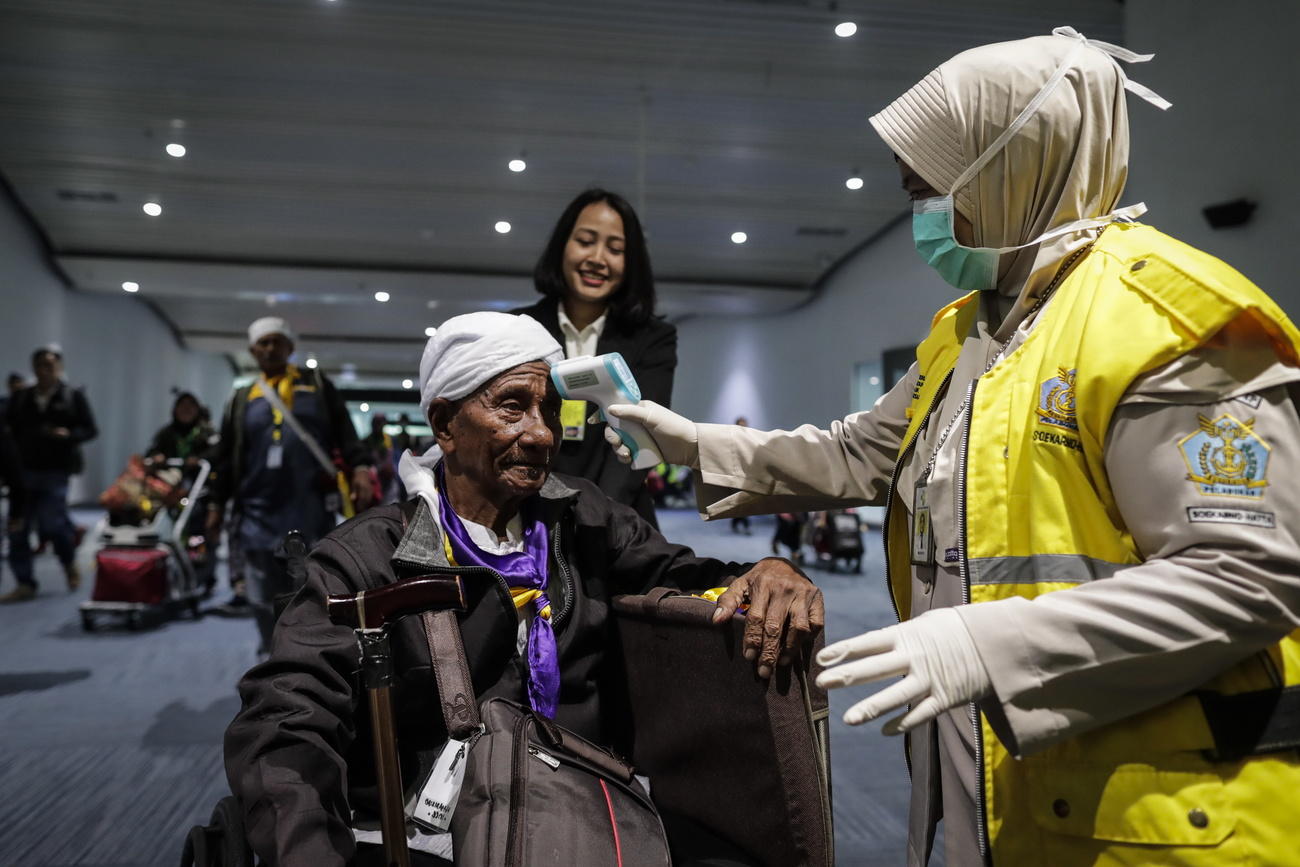 addetto dell aeroporto misura la temperatura di una persona anziana