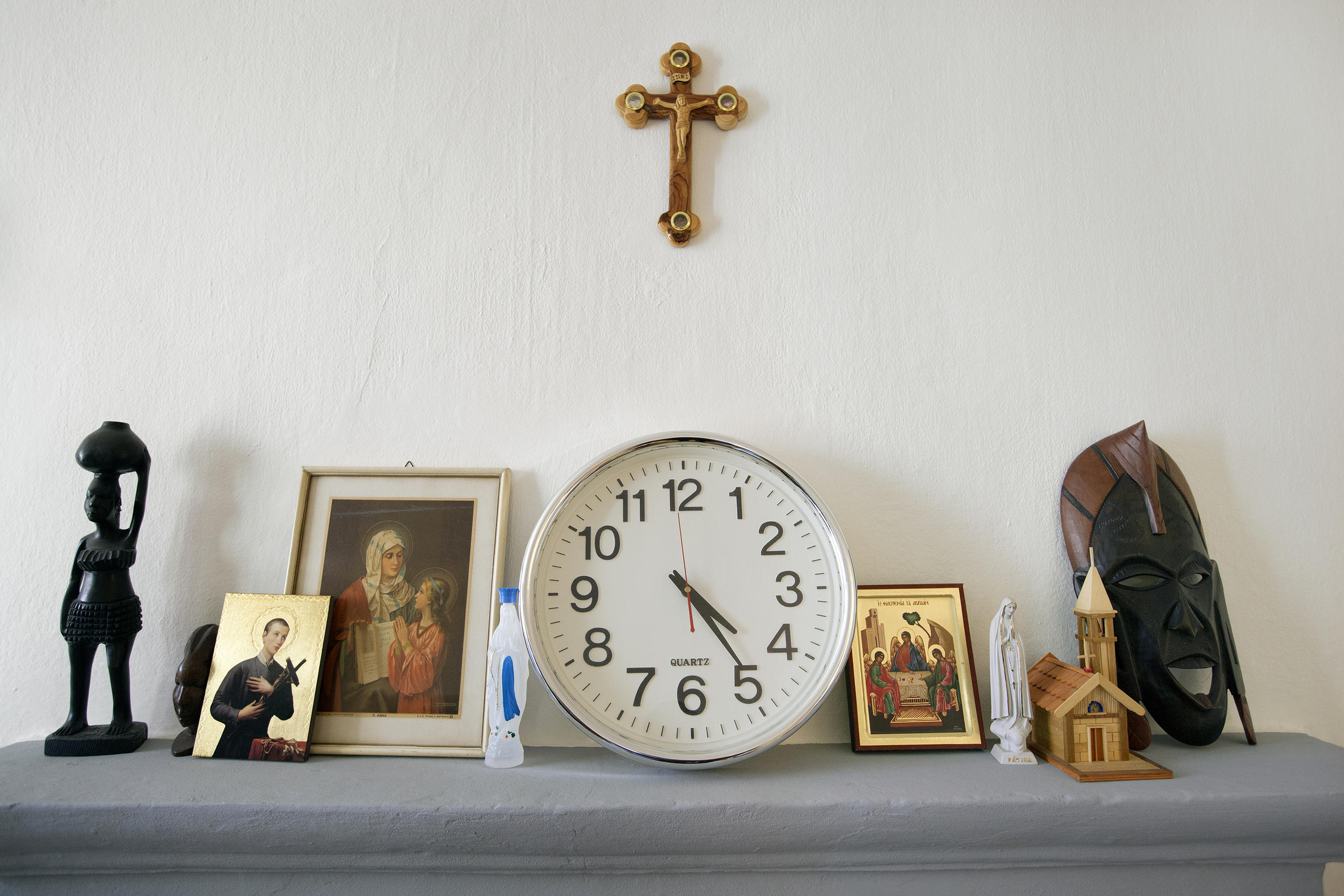 Kreuz über einem Tisch mit Fotos und Uhr