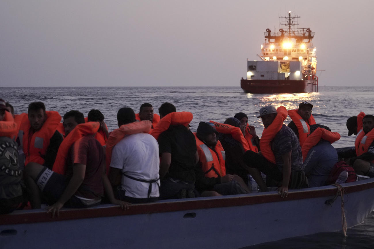 Migrants on an overcrowded wooden boat wait to be rescued in the Mediterranean Sea