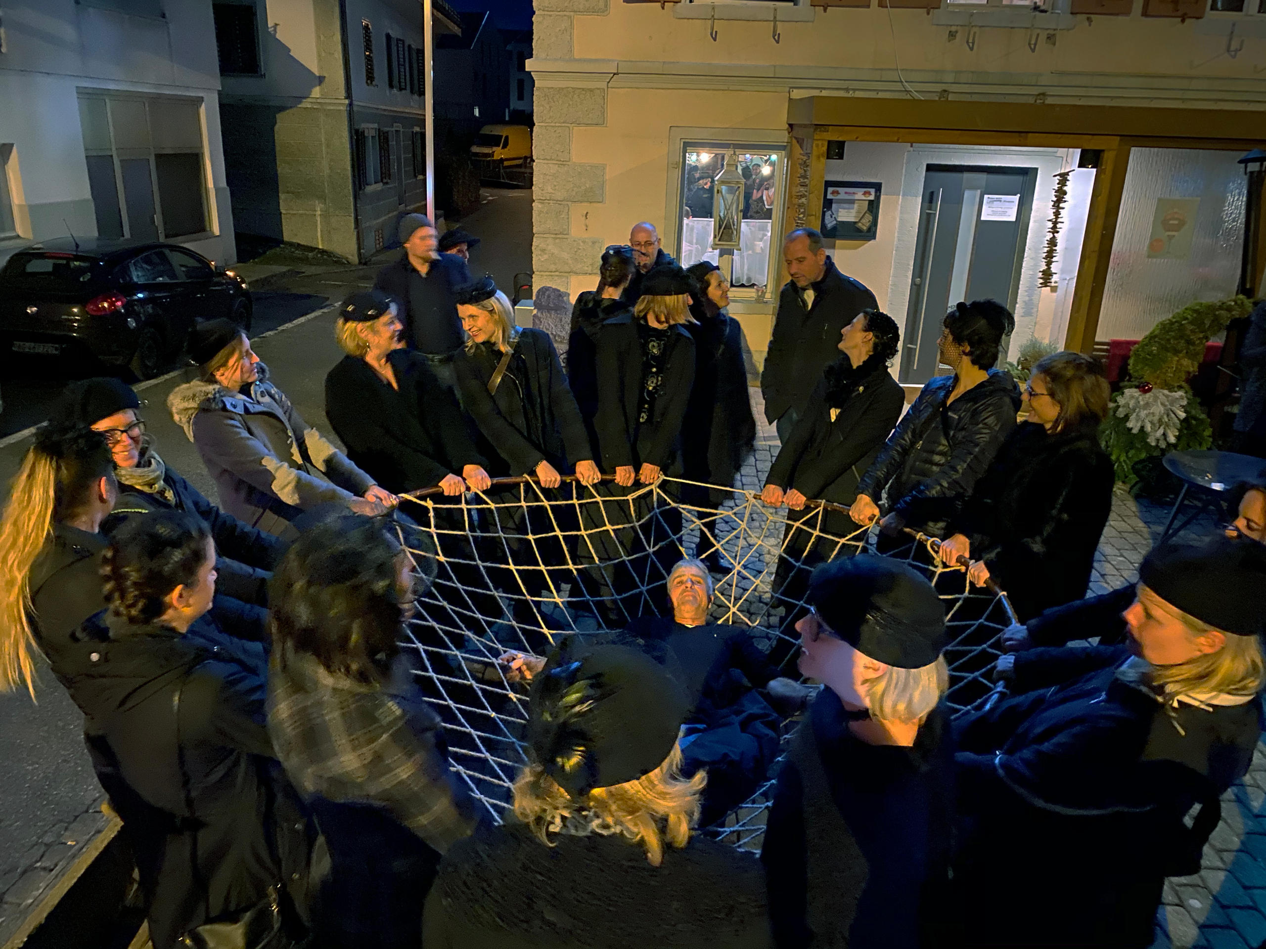 Man in net held by group of women