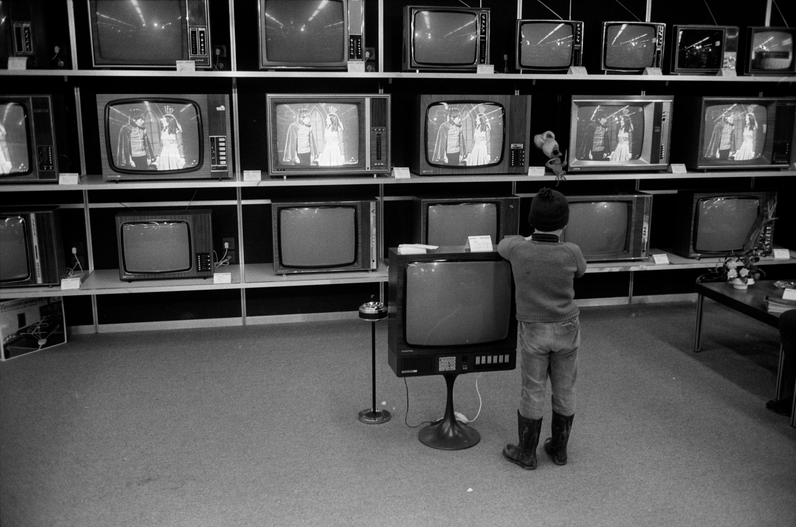 Un niño frente a un anaquel lleno de televisores