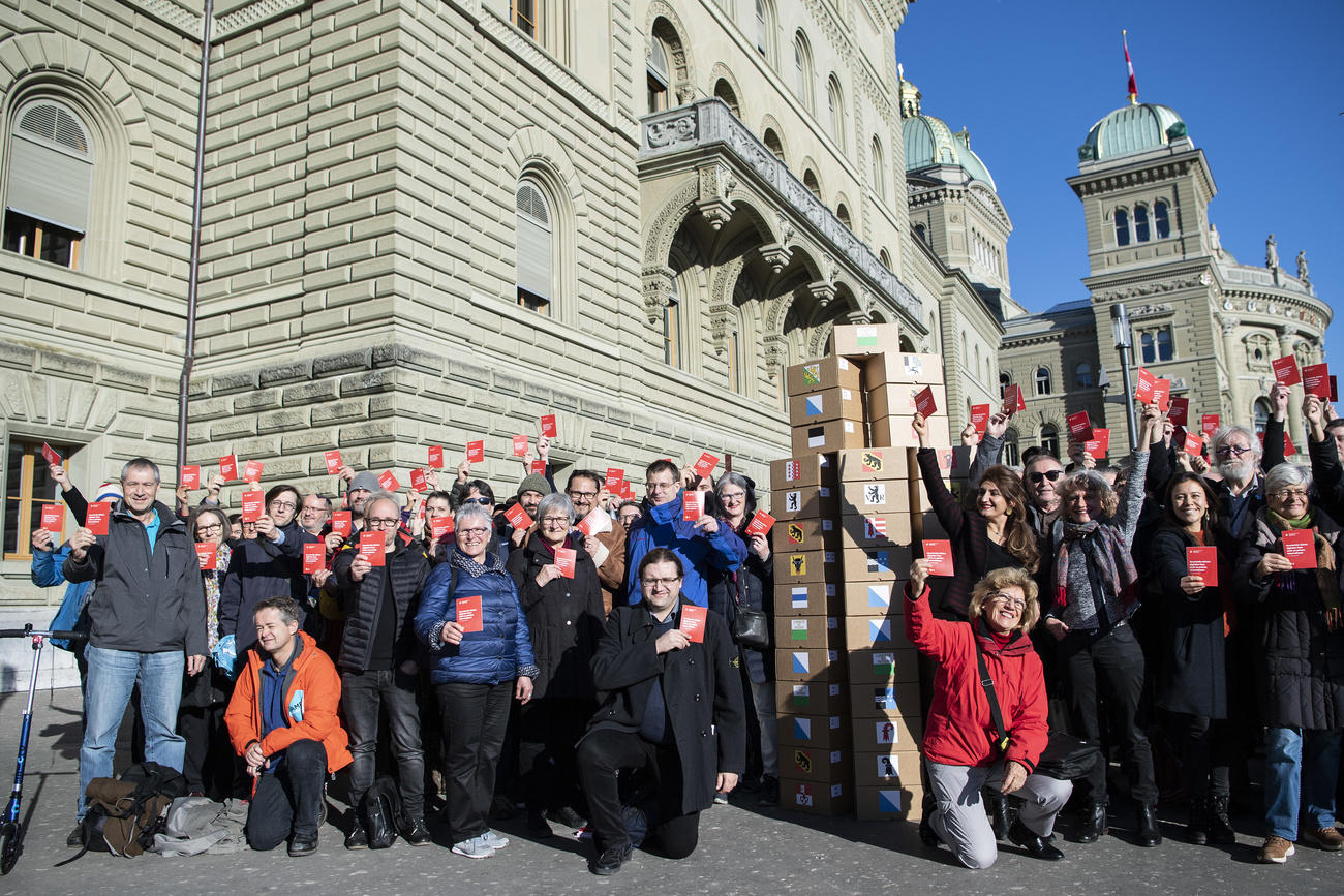 Group of people with red booklet in front of parliament building