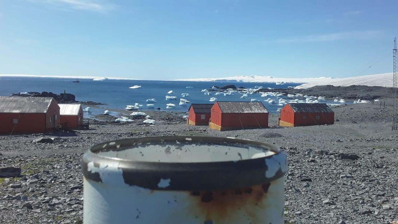 Spiaggia di sassi con costruzioni in legno; si intravvede l interno del continente completamente innevato