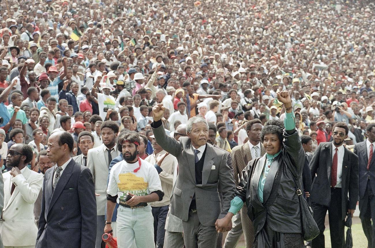 Mandela con il pugno alzato, folla sullo sfondo.