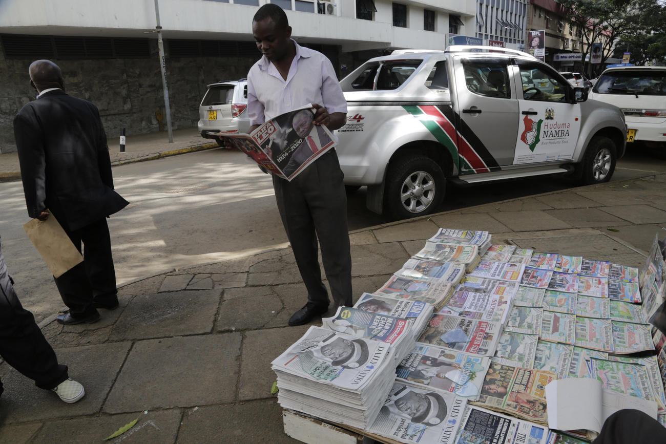 man with stacks of newspapers