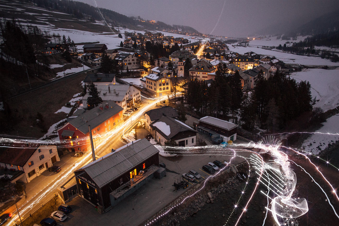Un villaggio di montagna fotografato di notte; aggiunte, in grafica, delle scie luminose che simboleggiano le telecomunicazioni