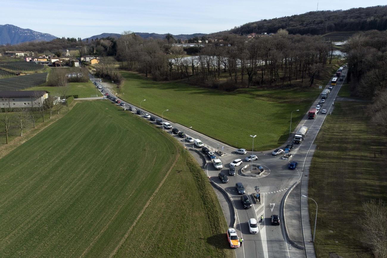 Rotatoria stradale, con coda su due delle tre strade che vi confluiscono, in aperta campagna vista dall alto