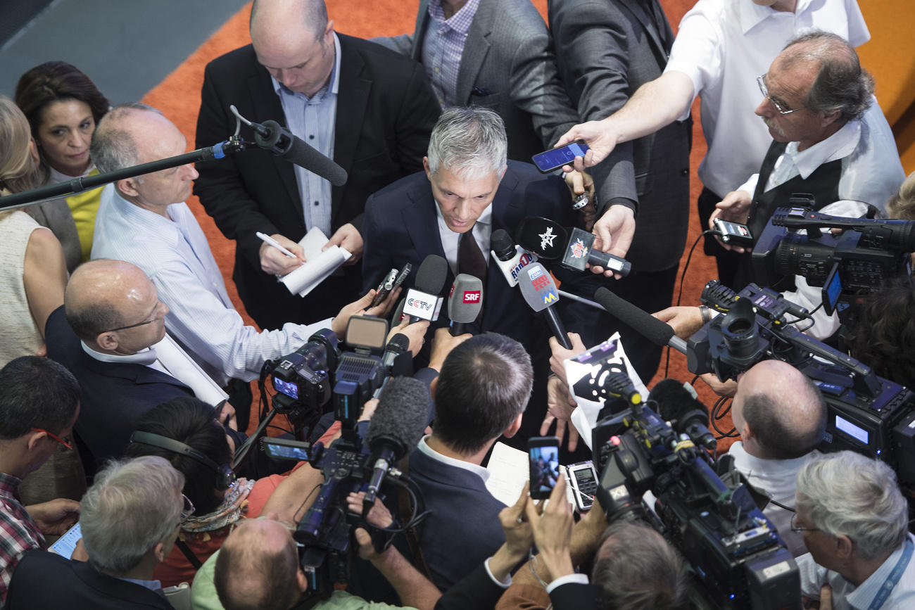 Lauber surrounded by journalists with cameras and microphones