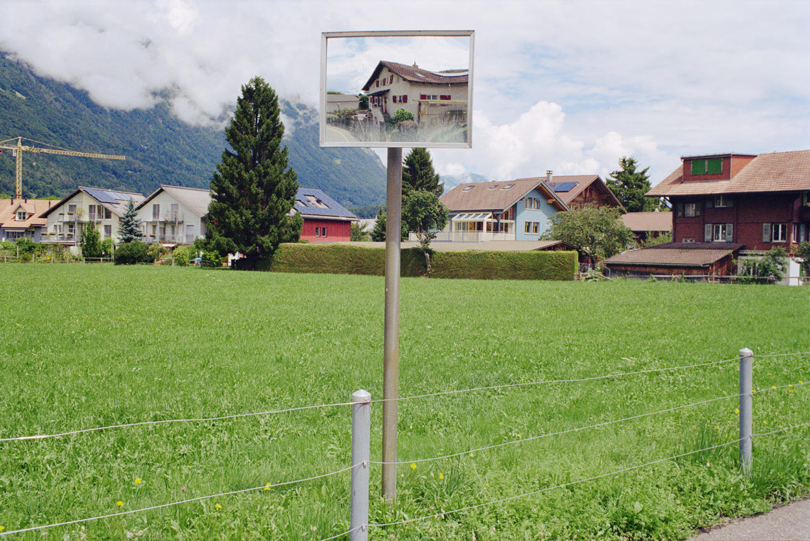 Paisagem com casa ao fundo e espelho na estrada