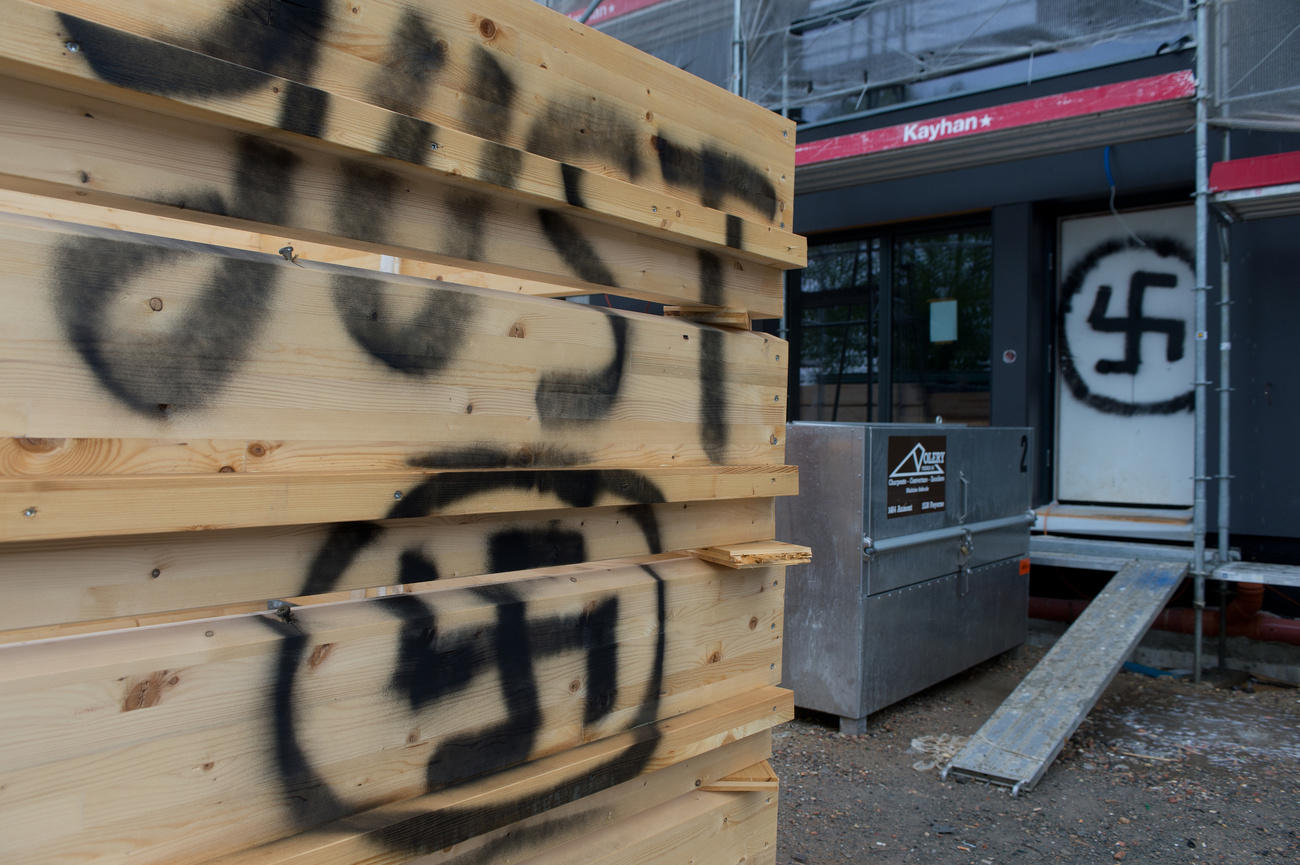 Eine Holzwand mit einem schwarzen Hakenkreuz.
